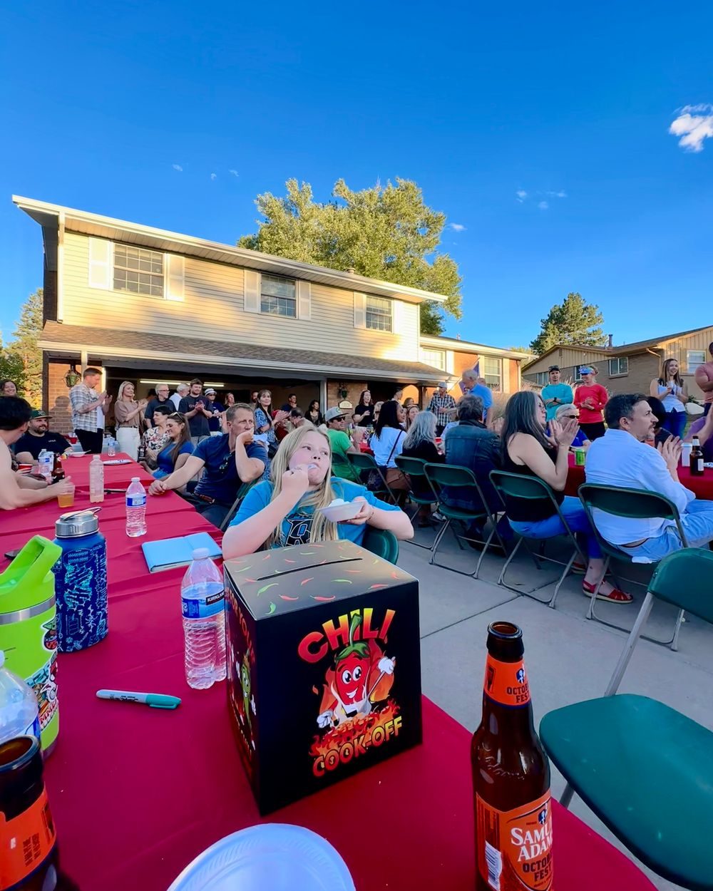 Chili cook-off voting box on a red tablecloth, with guests seated at long tables behind it